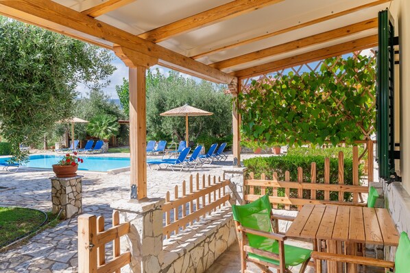 Un espace extérieur abrité comprenant une piscine, des chaises longues et une table en bois.
