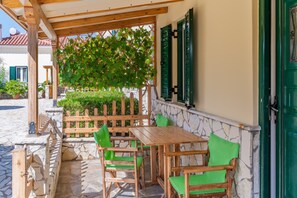 Une terrasse extérieure avec des meubles en bois, un mur en pierre et une porte verte.