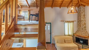 Un interior de madera con chimenea de piedra, un sofá y una escalera.