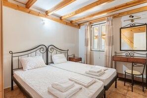 A bedroom with two beds, a wooden ceiling, a desk, and a mirror.
