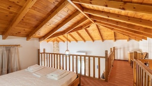 Un dormitorio con techo de madera, una cama, baranda de madera y vista al exterior.