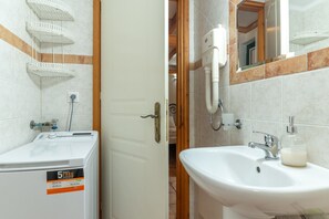 A bathroom with a white sink, a mirror, a towel rack, and a white washing machine.