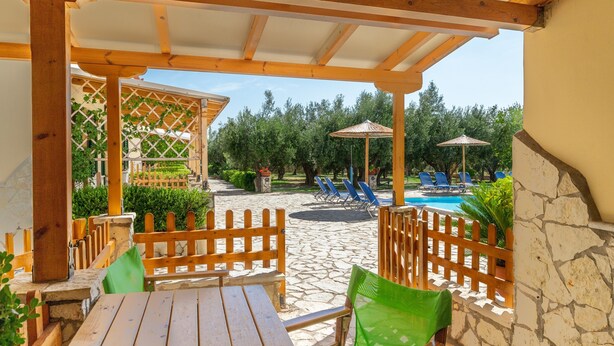 Un espacio al aire libre cubierto con piscina, muebles de madera y un sendero de piedra.