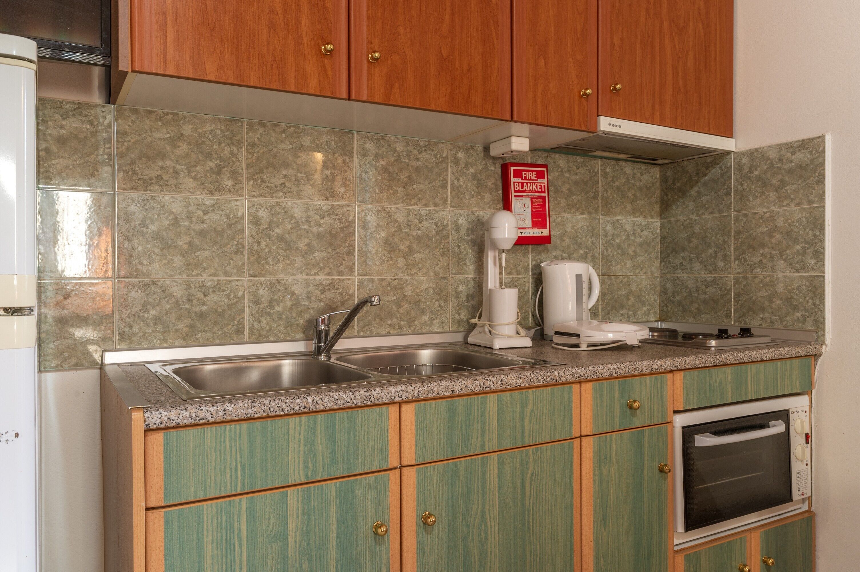 A kitchen with a double sink, a coffee maker, and a microwave.