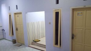 Un pasillo con puertas, un cubo de basura y suelo de baldosas.