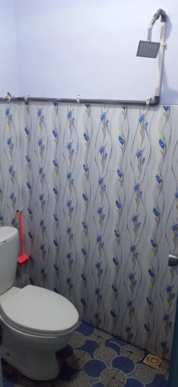 Une petite salle de bain avec des toilettes, une douche et des carreaux décorés.