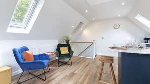 A modern kitchen with a high ceiling, skylights, a dining area with a bar stool, and a seating area with two chairs. - Beautiful Self Contained Annex in Toddington (Cheltenham)