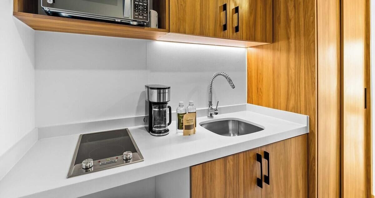 A modern kitchen with a built-in microwave, a coffee maker, and a sink.