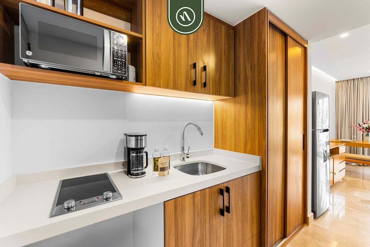 A modern kitchen with wooden cabinets, a microwave, a coffee maker, and a sink.
