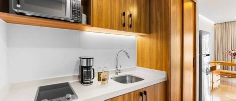 A modern kitchen with wooden cabinets, a microwave, a coffee maker, and a sink.