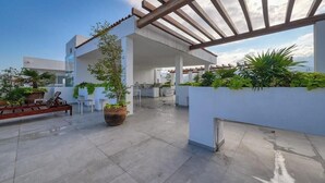A rooftop patio with a pergola, seating, and potted plants. - Amazing 1BR - Rooftop Pool in Versalles (Puerto Vallarta)