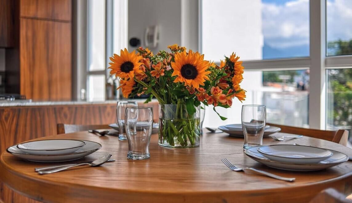 A dining table with plates, cutlery, and a vase of sunflowers.