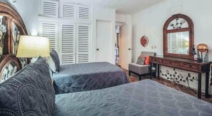 A bedroom with two beds, a dresser, a mirror, and a lamp.