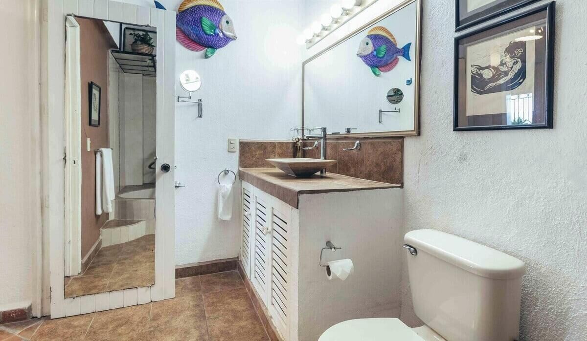 Une salle de bain avec un lavabo, des toilettes et un miroir.