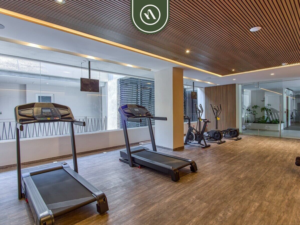 A modern gym with treadmills, stationary bikes, and a large mirror.