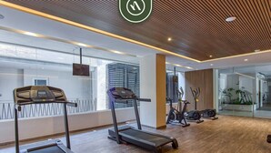 Una palestra moderna con tapis roulant, cyclette e un grande specchio.