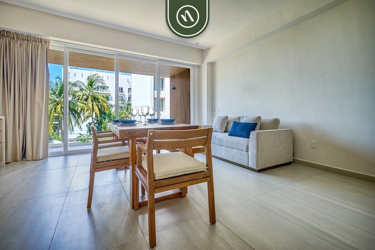 Una sala de estar moderna con comedor, ventanas grandes y vista a palmeras.