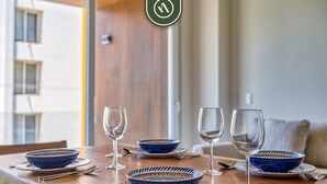 Un tavolo da pranzo con ciotole blu decorate e bicchieri da vino, una sedia di legno e vista su un edificio esterno.