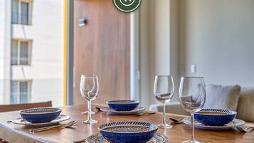 A dining table with blue patterned bowls and wine glasses, a wooden chair, and a view of a building outside.