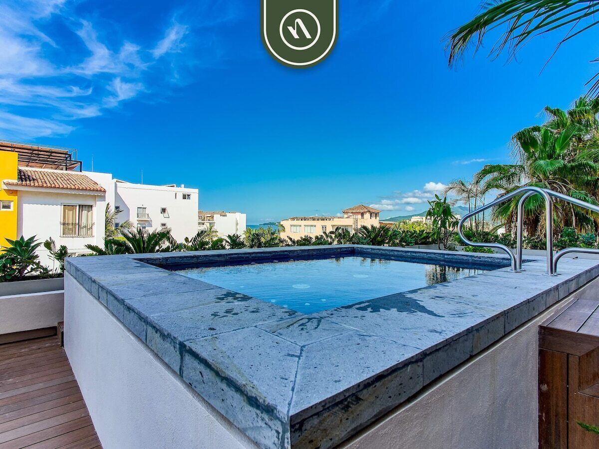 Una piscina en la azotea con vistas despejadas de los edificios y palmeras circundantes.