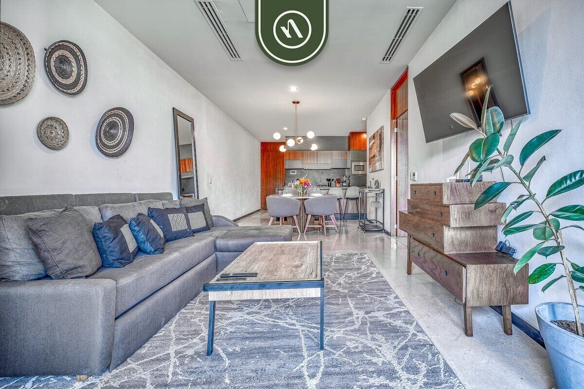 A modern living room with a sofa, coffee table, and a dining area with chairs.