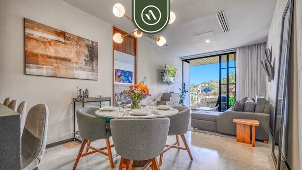 A modern living room with a dining area, a sofa, a TV, and a large window with a city view.
