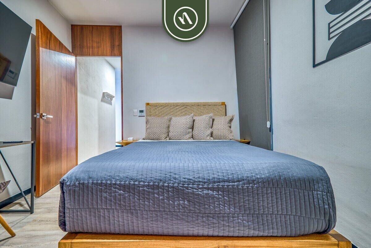 A bedroom with a bed, wooden wardrobe, and a wall-mounted light fixture.