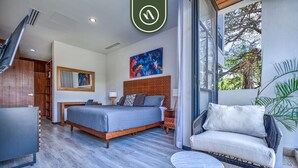A modern bedroom with a bed, bedside table, chair, and a view of the outdoors. - New 2BR Condo in Zona Romantica - Rooftop Pool (Puerto Vallarta)