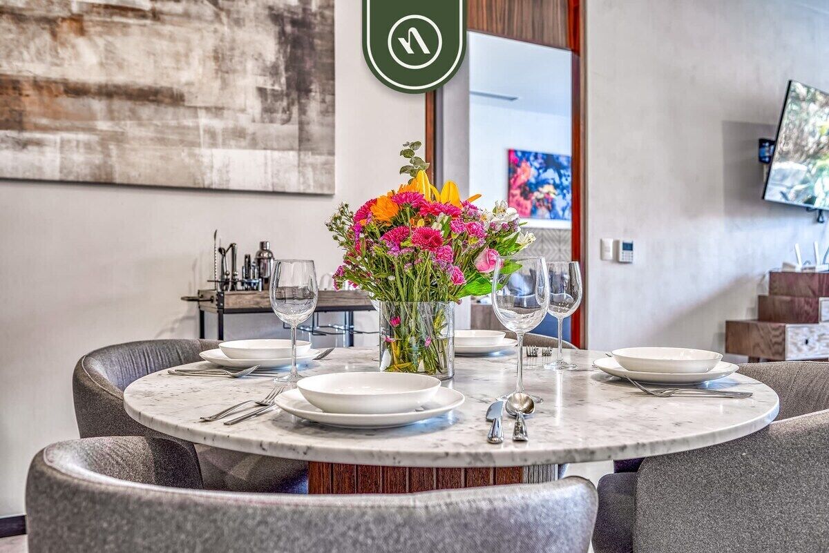 A dining area with a round table, chairs, and a vase of flowers.