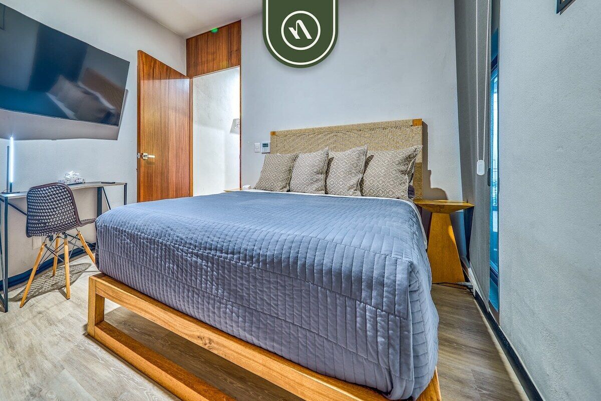 Moderni hotellihuone, jossa on suuri sänky, työpöytä ja televisio.