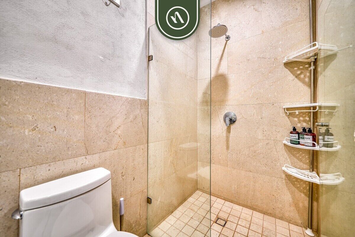 Ein modernes Badezimmer mit einer Duschkabine, einer Toilette und einem Ablagefach für Pflegeprodukte.