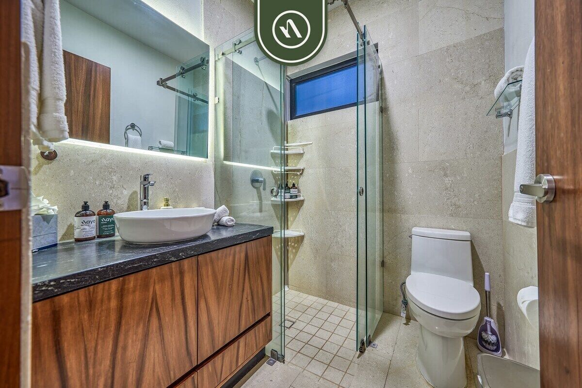 Une salle de bain moderne avec une douche à parois de verre, un lavabo blanc et des toilettes.