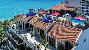 Un hotel con varias edificaciones de cúpulas azules, una piscina y vista al mar.