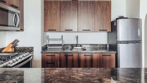 Una cocina moderna con armarios de madera, un refrigerador de acero inoxidable, una estufa a gas y una encimera de granito.