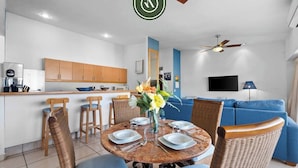 Un salon moderne comprenant un coin repas, une cuisine et un canapé bleu.