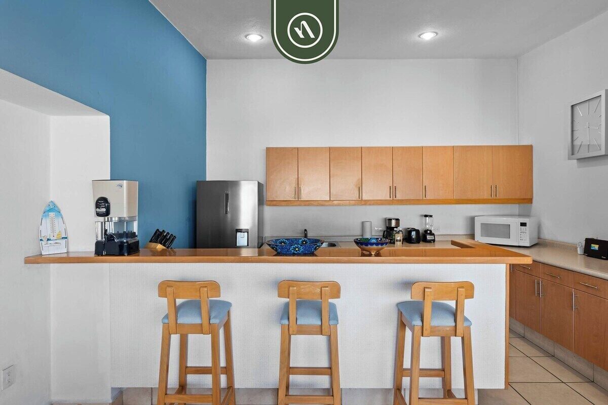 A modern kitchen with a central island, wooden cabinets, and bar stools.