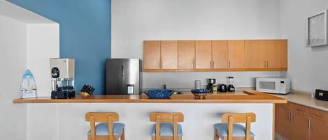 A modern kitchen with a central island, wooden cabinets, and bar stools.