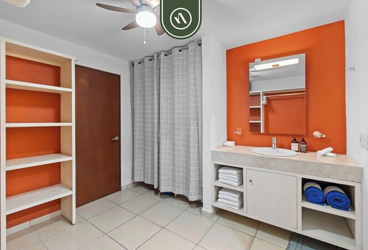 A bathroom with a white vanity, a mirror, a shower curtain, and a ceiling fan.