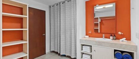A bathroom with a white vanity, a mirror, a shower curtain, and a ceiling fan.