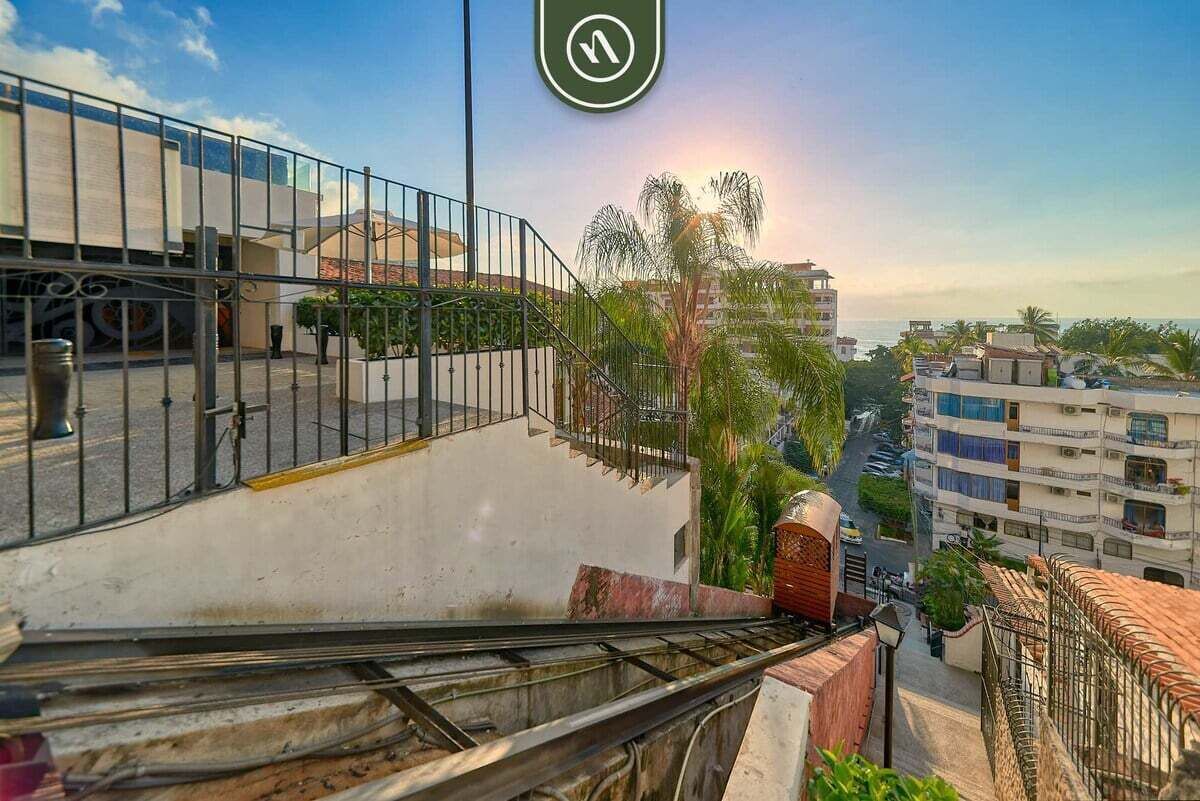 A staircase leading to a balcony overlooking a street with buildings and a clear sky.