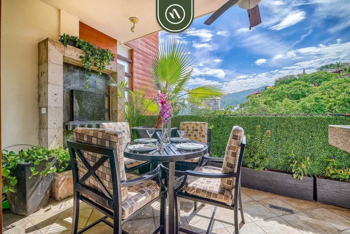 An outdoor patio with a round table, four chairs, and a decorative vase.