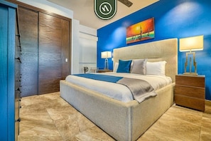 Une chambre à coucher avec un grand lit, deux tables de chevet, une commode et un tableau au mur.