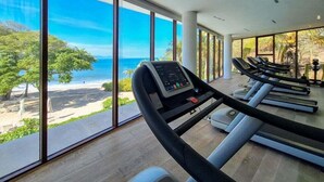 A gym with treadmills and a large window overlooking a beach. - Amazing Condo - Beach Access - Spa - Pool (Punta de Mita)