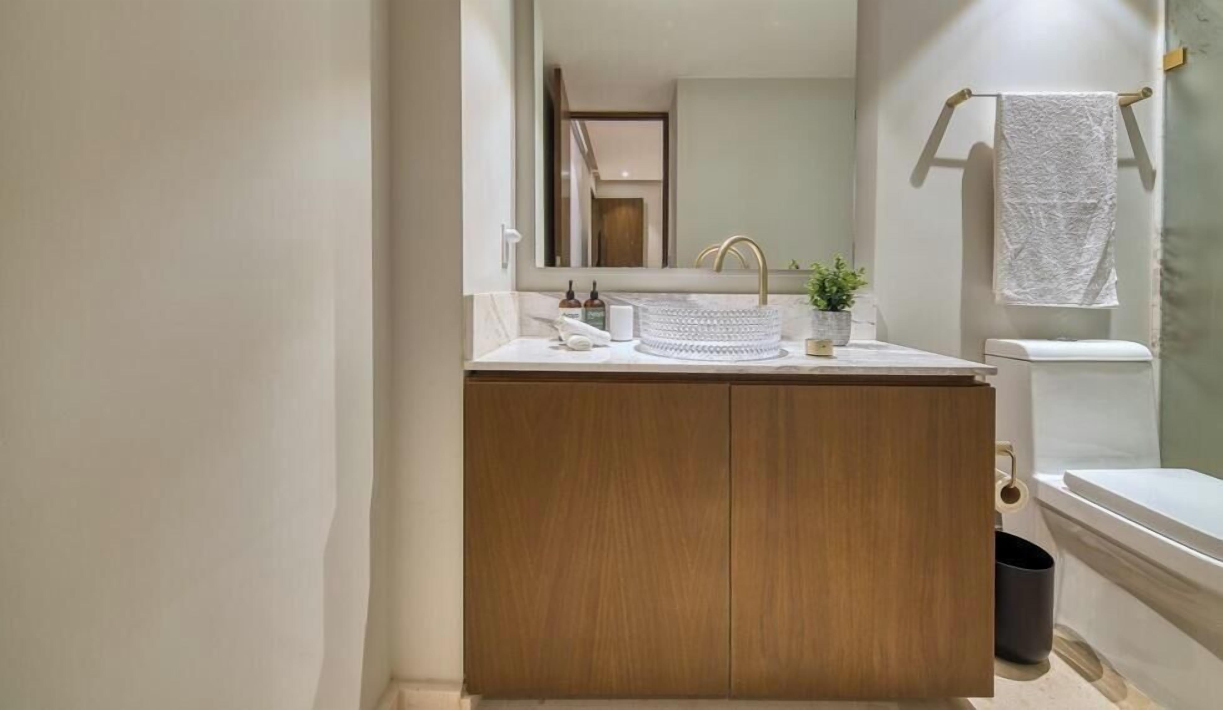 A bathroom with a wooden vanity, a sink, a mirror, and a towel rack.