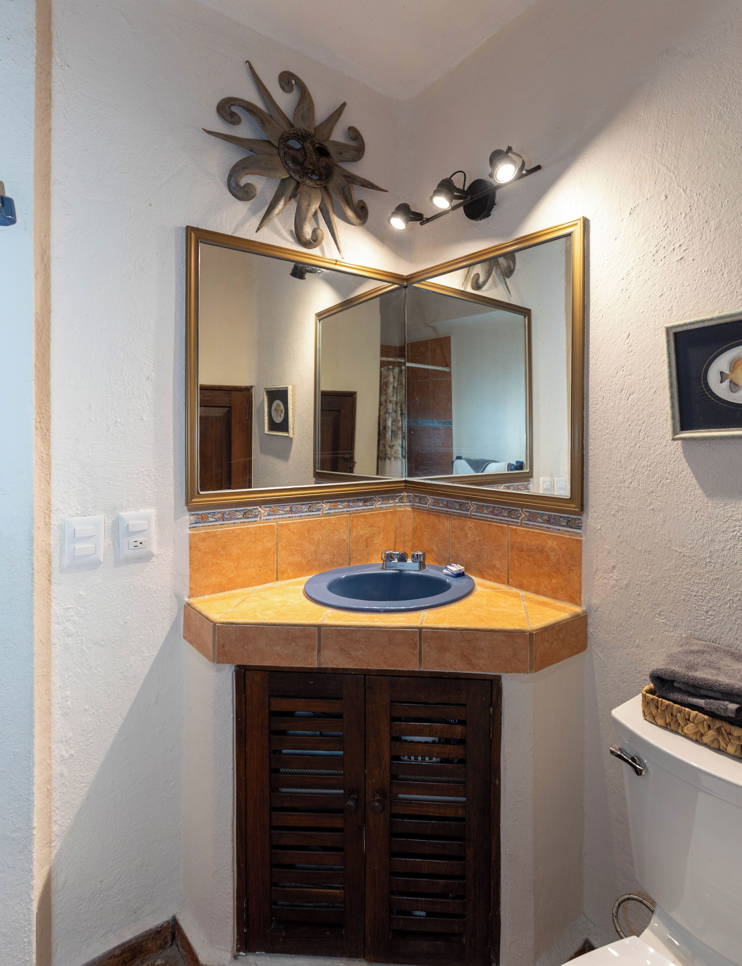 Une salle de bain équipée d’un lavabo, d’un miroir et d’un élément décoratif mural.