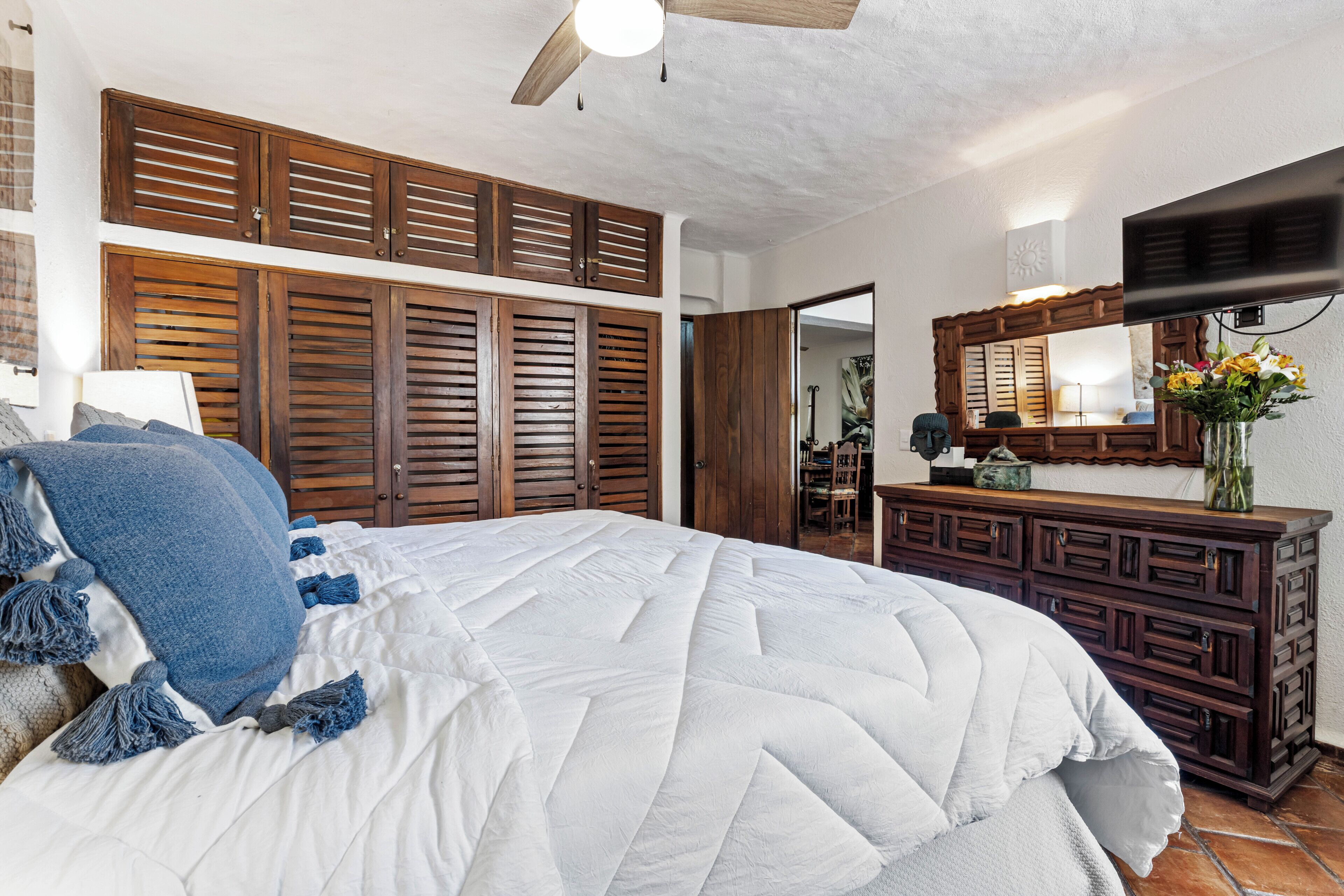 A bedroom with a large bed, wooden wardrobe, and a TV on a dresser.