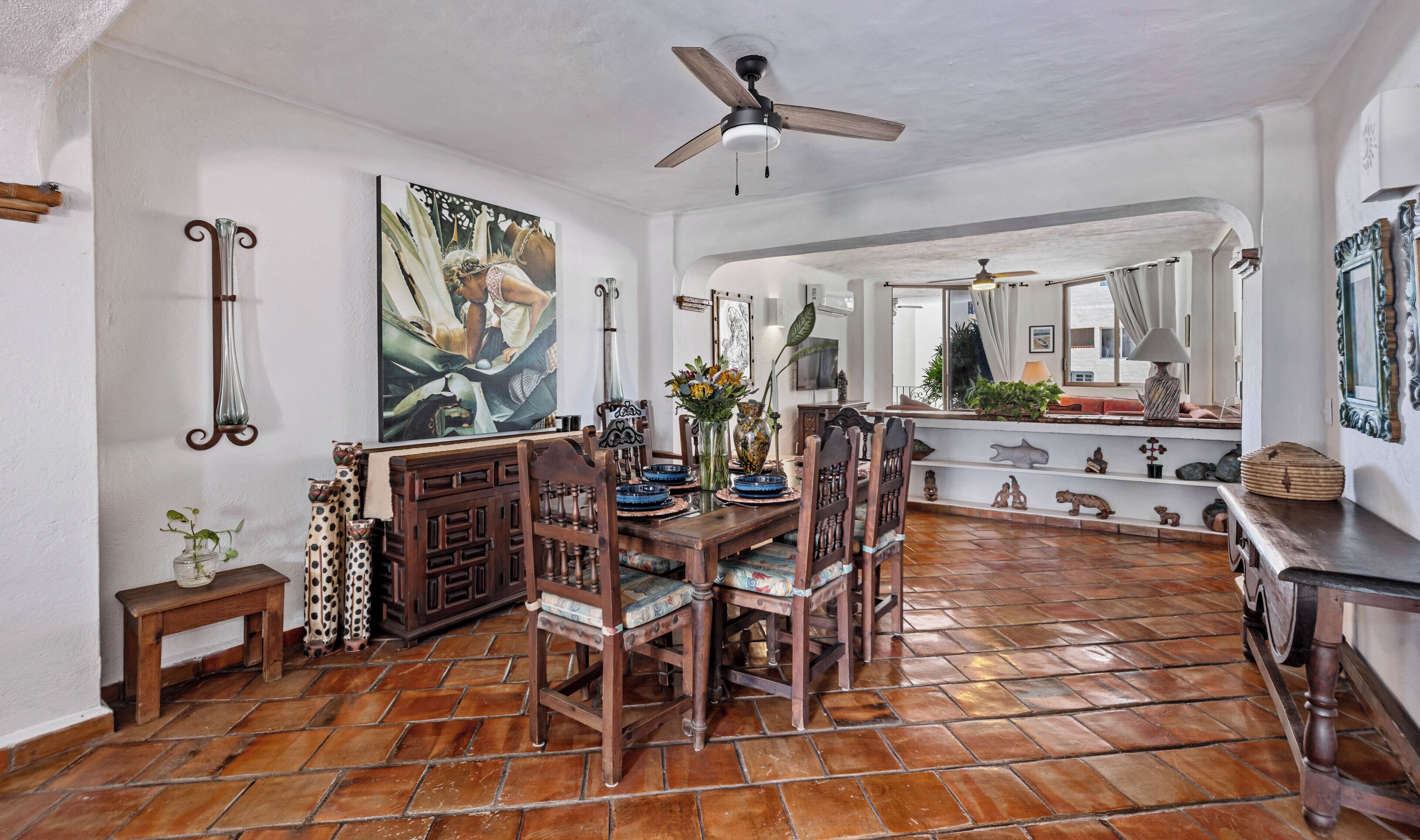 A dining area with a wooden table, chairs, and a ceiling fan.
