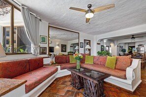 Een woonkamer met een bank, een salontafel en een plafondventilator.