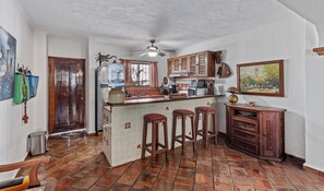 A kitchen with a central island, wooden stools, a refrigerator, and a ceiling fan. - Ocean View 2Br Condo-balcony-beach-pool - 303 (Puerto Vallarta)