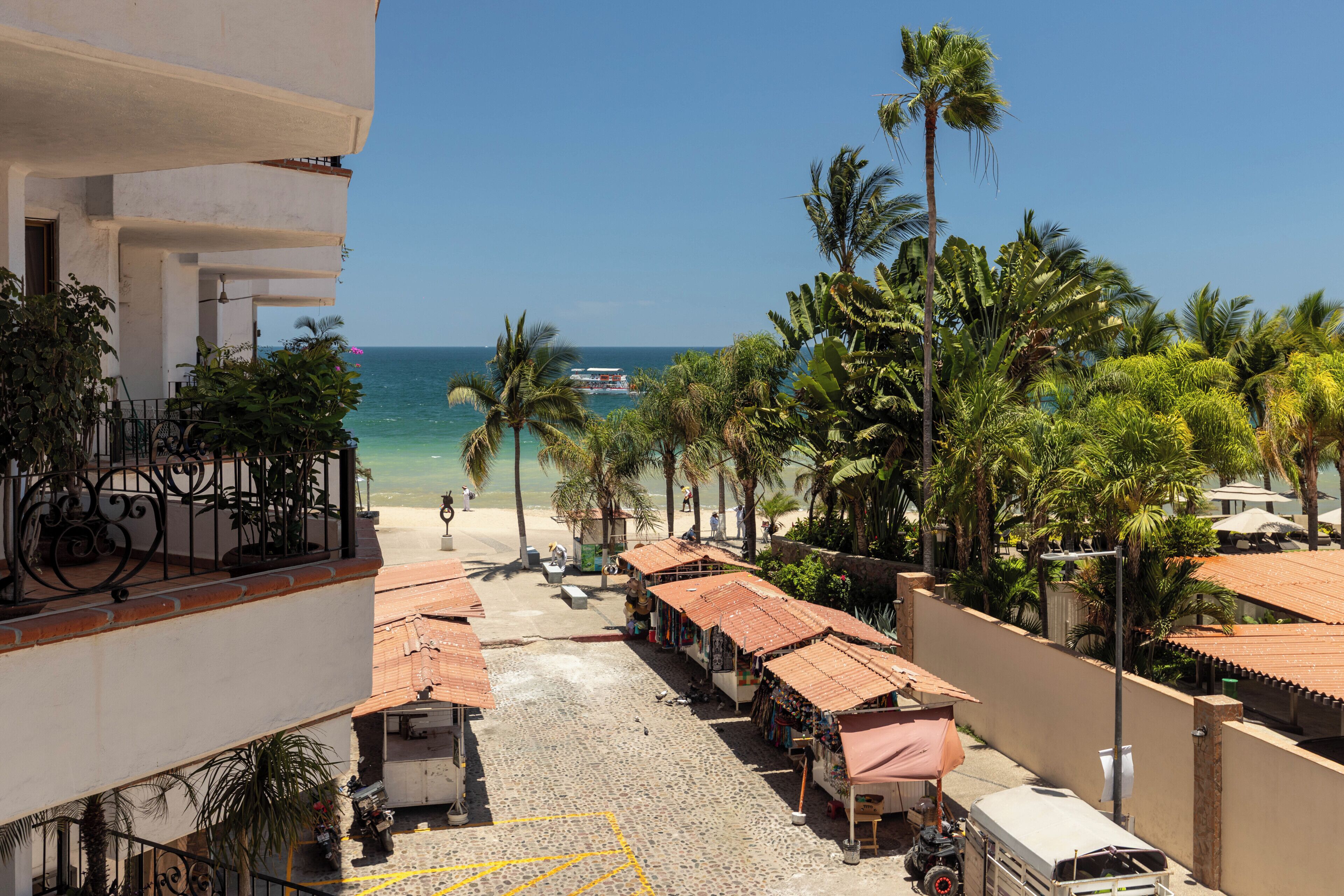 Una calle frente a la playa, con edificios, palmeras y vistas al océano.